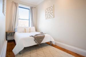 ボストンにあるClassic furnished 1BR in Fenway in Brownstone Bldgのベッドと窓のある白い寝室