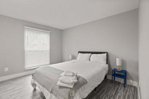 a white bedroom with a bed and a blue table at Perfect Getaway Comfort & Stunning City Views in Rochester Hills