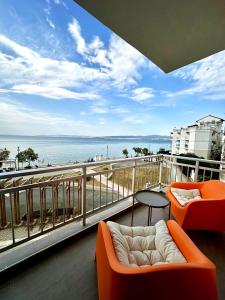 a balcony with orange chairs and a table and the ocean at Seebloom in Perea