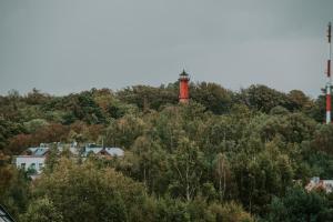 a red lighthouse on top of a hill with trees at Ostrowo LATEM in Ostrowo