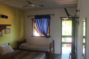 a bedroom with two beds and a window with a blue curtain at Pousada Arco Íris in Conceição da Barra +2 photos