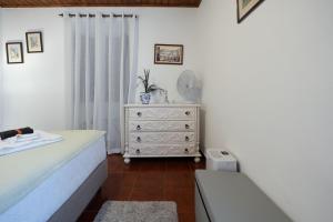 a bedroom with a bed and a dresser with a mirror at WelcomeBuddy - Casa do Moinho Garden & Sea Retreat in Ponta Delgada