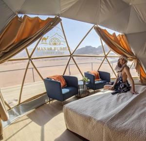 a woman sitting on a bed in a tent at Manar Bubble Luxury Camp in Wadi Rum