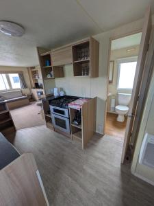 a kitchen with a stove and a toilet in a room at Cosy 8 Berth Caravan At Ty Mawr Holiday Park, North Wales Ref 86008D in Conwy