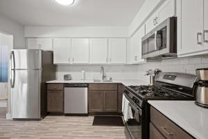 ロチェスターヒルズにあるPeaceful Rochester Escape Perfect for Familiesの白いキャビネットとステンレス製の冷蔵庫を備えたキッチン +13枚の写真