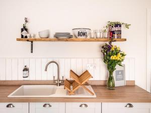 een aanrecht met een wastafel en een vaas met bloemen bij Garden Cottage, Cosy, Private, Short drive to beach in North Walsham +49 foto's