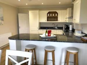 una cucina con mobili bianchi e un bancone con sgabelli di Pen Y Frith Bungalow a Prestatyn Altre 4 foto