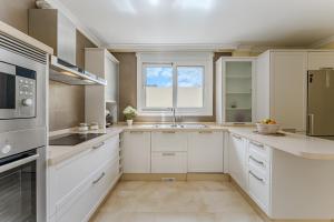 a kitchen with white cabinets and a sink at Villa Jardin del Sol in Adeje