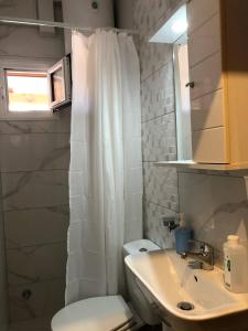 Un baño con una cortina de ducha blanca y un lavabo. en Dina Studio Apartments, en Pefkohori