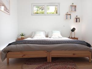 a bed in a white room with a window at L'Olivier, appartement cosy entre mer et forêt in Saint-Michel-Chef-Chef