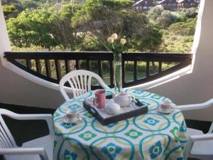 a table with a vase of flowers on a balcony at Grand Yellow Apartment in Port Alfred