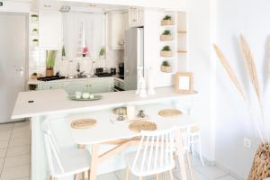 a white kitchen with a white counter and stools at Julie's Home Παραλία Ακράτας in Paralía Akrátas
