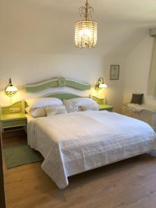 een slaapkamer met een groot wit bed en een kroonluchter bij Mauthnerhube Ferienwohnung mit Sauna, Whirlpool, Hüttenfeeling in Sankt Oswald ob Eibiswald