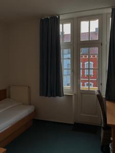 a bedroom with a bed and a window and a desk at Stadthotel Kolpinghaus - Vier Ecken in Werne an der Lippe