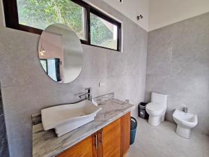 a bathroom with a sink and a mirror and a toilet at Apartament at Infiniti Hotel in Puerto Viejo