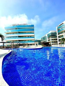 a large blue swimming pool in front of a building at Hospedatom - Cobertura Vista Mar com Piscina Arraial do Cabo in Arraial do Cabo