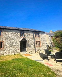 a stone building with benches in front of it at Penrhyn Cottage in Penrhyn Bay