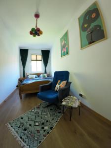 a living room with a blue chair and a bed at Stacja Srebrna Góra in Srebrna Góra