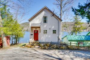 a white house with a red door next to a lake at Paddle, Swim and Hike Family Lake House in Vermont in Wallingford