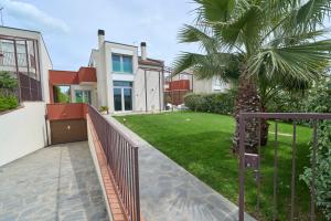 a house with a fence and a palm tree at SunStyle House Villetta Rimini con Giardino e Park in Casalecchio