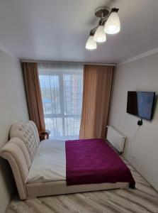 a bedroom with a large bed with a purple blanket at Яровиця кімната та кухня студія in Luts'k