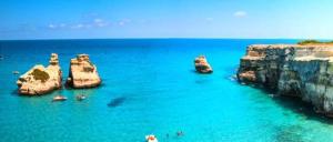 a group of people in the water near some rocks at Casa vacanze Donna VALERIA in San Foca