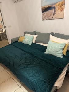 a bed with a green blanket and pillows on it at L éden mer et piscine appartement 53 m2 in Saint-Aygulf +18 photos