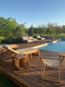 a wooden deck with benches next to a swimming pool at Maison Dulcis in Saint-Maixant