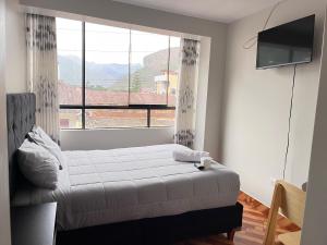 a bedroom with a bed and a large window at Hostal El Mariscal in Urubamba +7 photos