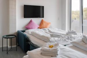 a room with two beds with pillows and a tv at Skyrise Apartments - Stilvoll wohnen, entspannt genießen in Bad Wörishofen