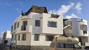 een busje geparkeerd voor een wit gebouw bij Casa Maday in Cotillo