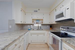 a white kitchen with white cabinets and a sink at Pelican's Post -Ocean, Pool Views, Private Balcony in North Topsail Beach