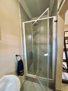 a glass shower in a bathroom with a sink at Villa Bloemé Guesthouse in Bloemfontein