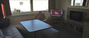 a living room with a couch and a tv at Moonstone Hayling Island Holiday Park in South Hayling