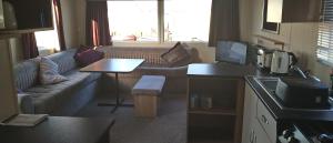a kitchen and living room with a couch and a table at Moonstone Hayling Island Holiday Park in South Hayling
