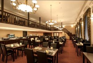 a dining room with tables and chairs and chandeliers at Spa Hotel MILLENIUM Karlovy Vary in Karlovy Vary