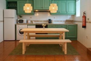 a kitchen with green cabinets and a table with a bench at Peach House T2 Fireplace in Ferro