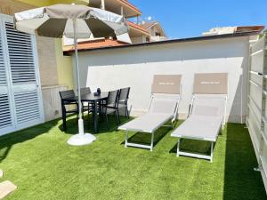 a patio with a table and chairs and an umbrella at NOVELLA DEL MAR prima fila dal mare in Grottammare