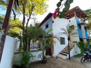 a white house with palm trees in front of it at Jardim encantado hospedagens in Pipa