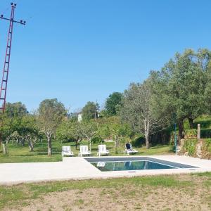 a swimming pool in a park with two white chairs at Casa da Ramada, Turismo Espaço rural. in Ponte de Lima