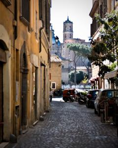 eine Kopfsteinpflasterstraße in einer Stadt mit einem Uhrturm in der Unterkunft Madonna dei Monti in Rom