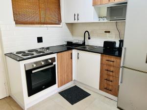 Una pequeña cocina con estufa y fregadero. en Camarque - Umdloti's Ocean Escape, en Umdloti