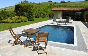 een terras met een tafel en stoelen naast een zwembad bij Il casotto nelle Langhe in Farigliano
