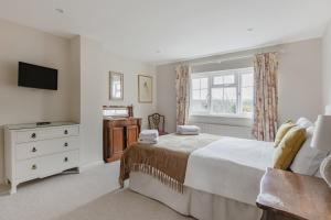 ein Schlafzimmer mit einem Bett, einer Kommode und einem Fernseher in der Unterkunft A Charming Cottage, Christow Dartmoor National Park in Christow