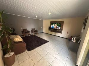 a living room with a couch and a flat screen tv at Casa grande com piscina in Foz do Iguaçu