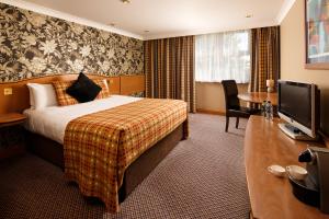 a hotel room with a bed and a desk with a television at Jupiter Hotel Wetherby in Wetherby