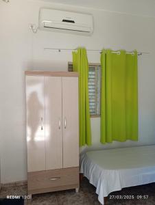 UruaçuHotel Ouro Fino的一间卧室配有床和带绿色窗帘的橱柜