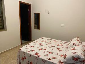 a bed with a white blanket with red flowers on it at Edícula em Jaú próxima do centro e do HAC in Jaú +17 photos