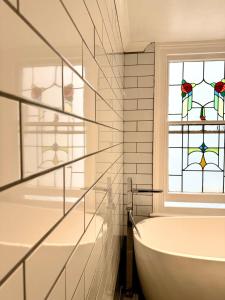 a bathroom with a tub and a stained glass window at Seafront Flat By Mrs Butler Short Term Rental Brighton in Brighton & Hove +18 photos