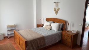 a bedroom with a wooden bed and a night stand at Breeze House Almograve - Rooms on Fishermen's Trail in Almograve